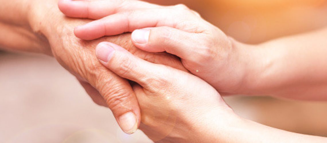 Caregiver, carer hand holding elder hand in hospice care. Philanthropy kindness to disabled concept.